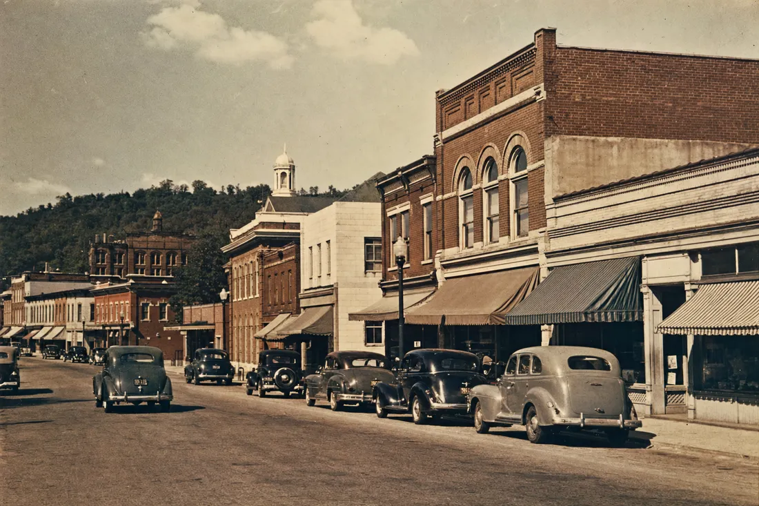 Mid-1940s small-town Kentucky main street with brick storefronts and period cars